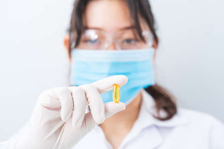 Close up Scientist hands putting in nitrile latex gloves holding Omega 3 capsule
