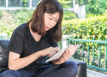 Young girl studying online from digital tablet on the sofa in parlor at home