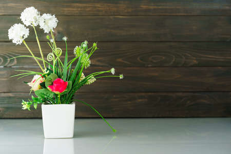 Artificial flower vase bouquet over table against wood wallの写真素材