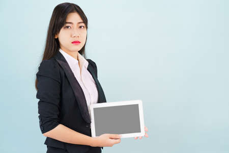 Young women in suit holding her digital tablet standing against blueの写真素材