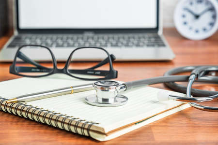 Medical stethoscope for doctor checkup with laptop computer on doctor note pad as medical conceptの写真素材