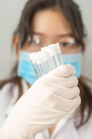 Technician scientist analyzing holding test tube in laboratory for testing it on COVID, COVID-19, coronavirus virus analysisの写真素材