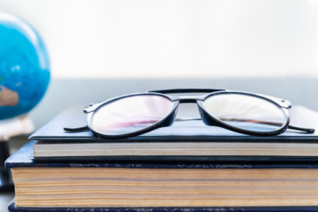Reading glasses put on hardcover books over wooden tableの写真素材