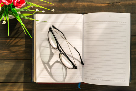 Reading glasses put on open book over wooden tableの写真素材