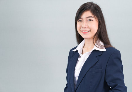 Portrait of asian business woman standing isolated on gray backgroundの写真素材