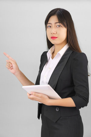 Young Asain women long hair in suit standing using her digital tablet computer  and pointing fingerの写真素材