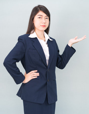 Asian woman in suit open hand palm gestures with empty space isolated on gray backgroundの写真素材