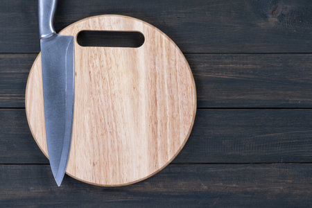 Close up kitchen knife and wooden round empty cutting board on a wooden table