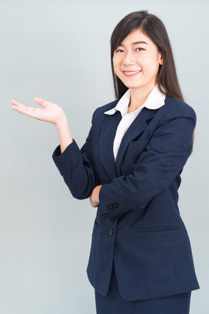 Asian woman in suit open hand palm gestures with empty space isolated on gray backgroundの写真素材