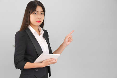 Young Asain woman long hair in suit standing using her digital tablet computer  and pointing fingerの写真素材