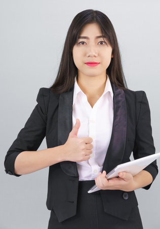 Young Asain woman long hair in suit standing using her digital tablet computerの写真素材