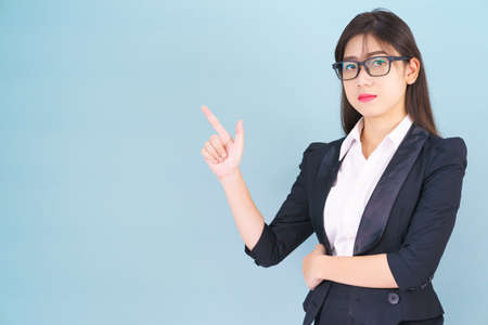 Asian business woman in suit with finger pointing up on blue backgroundの写真素材