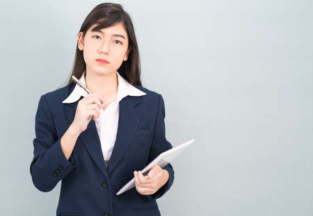 Asian woman in suit using computer digital tablet isolated on gray backgroundの写真素材