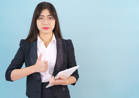 Young woman standing in suit holding her digital tablet computorの写真素材