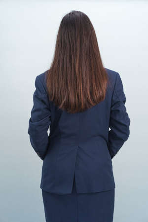 Asian woman wearing a suit in studio from behindの写真素材