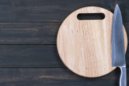 Close up kitchen knife and round cutting board on a wooden tableの写真素材