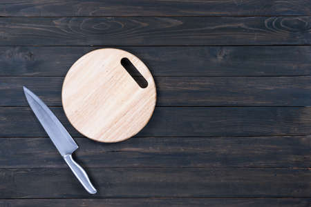 kitchen knife and wooden round empty cutting board on a wooden table close upの写真素材