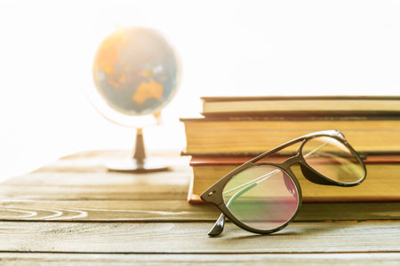 Reading glasses put on hardcover books over wooden tableの写真素材