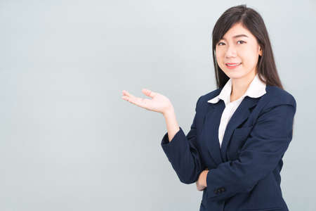 Asian woman in suit open hand palm gestures with empty space isolated on gray backgroundの写真素材