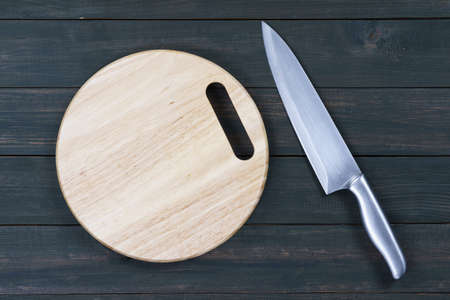 Close up kitchen knife and wooden round empty cutting board on a wooden tableの写真素材