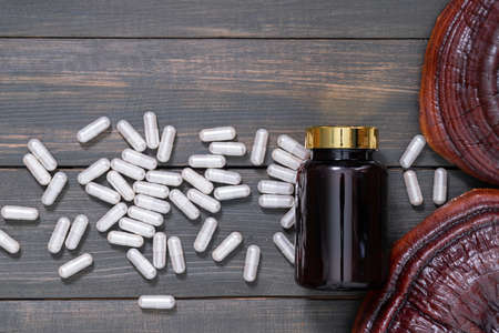 Close up of Ling zhi mushroom, Ganoderma lucidum mushroom and capsule with bottle mockup on wood tableの写真素材
