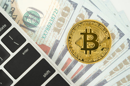 Golden Bitcoins coin and  US banknotes keyboard computer. Close up of metal shiny bitcoin crypto currency coins and US dollarの写真素材