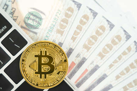 Golden Bitcoins coin and  US banknotes keyboard computer. Close up of metal shiny bitcoin crypto currency coins and US dollarの写真素材