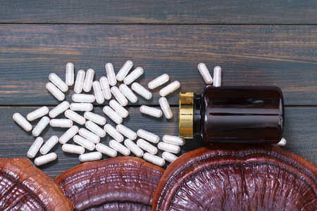 Close up of Ling zhi mushroom, Ganoderma lucidum mushroom and capsule with bottle mockup on wood tableの写真素材