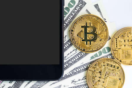 Top view Bitcoins coin and  US banknotes of one hundred dollars with smartphone. Close up of metal shiny bitcoin crypto currency coins and US dollarの写真素材