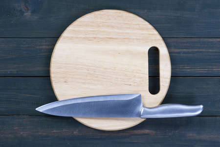 Close up kitchen knife and wooden round empty cutting board on a wooden tableの写真素材