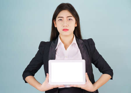 Young asian women in suit holding her digital tablet standing against green backgroundの写真素材