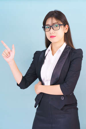 Asian business woman in suit with finger pointing up on blue backgroundの写真素材