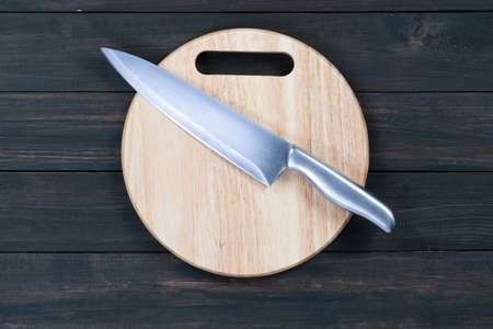 Close up kitchen knife and wooden round empty cutting board on a wooden tableの写真素材