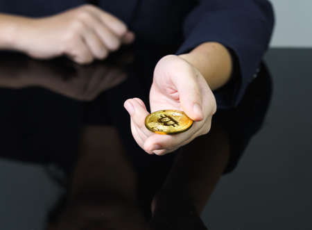 Close up of businesswoman holding some pieces of golden Bitcoin token , Bitcoin is one of the popular cryptocurrencyの写真素材