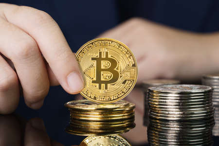 Close up of businesswoman holding some pieces of golden Bitcoin token , Bitcoin is one of the popular cryptocurrencyの写真素材