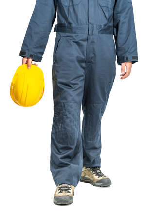 Cloes up Worker standing in blue coverall holding yellow hardhat isolated on white backgroundの写真素材