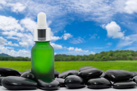 Serum oil bottle dropper mock up or essential oil with black stone agent green grass field and blue skyの写真素材