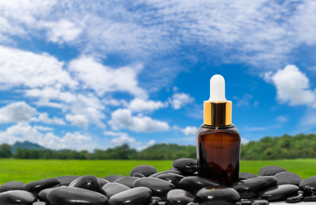 Serum oil bottle dropper mock up or essential oil with black stone agent green grass field and blue skyの写真素材
