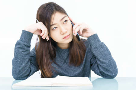Woman long hair Woman using mobile phone and  writing notebook on white backgroundの写真素材
