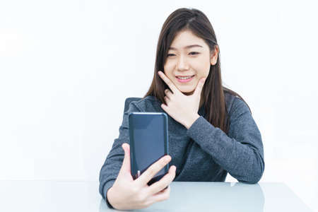 Woman long hair Woman using mobile phone and  writing notebook on white backgroundの写真素材