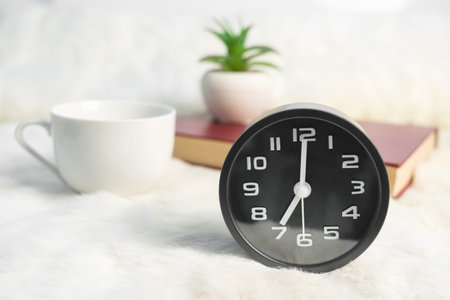 Black alarm clock and coffee cup  with book on table,Coffee time in the morningの写真素材