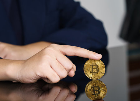 Close-up of finger touching golden bitcoin coin. Cryptocurrency and future money conceptの写真素材