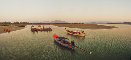Many small fishing boats in the sea during sunset in Thailandの写真素材