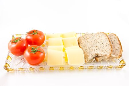 Picture of tomatoes, cheese, and some bread on a glass plate.の写真素材