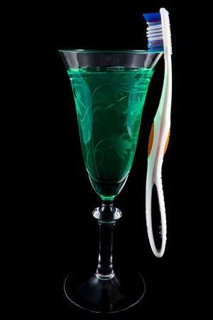 Picture of moutwash in a wine glass with a tooth brush hanging on the sideの写真素材