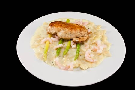 Picture of a dinner plate with chicken, asparges, pasta and some shrimpsの写真素材