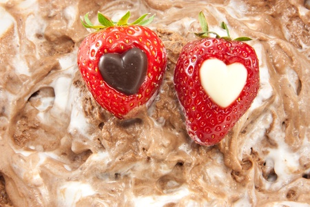 Picture of two strawberries with a heart center laying on mixed up chocolate mousseの写真素材