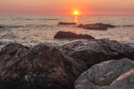 Sunset over the sea among the rocksの写真素材