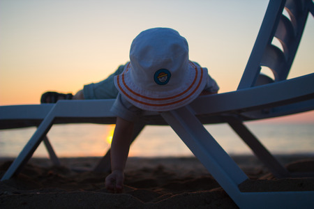 baby lying on a lounger on the beach and touch the sandの写真素材
