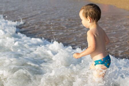 a little boy having fun in the sea on the wavesの写真素材